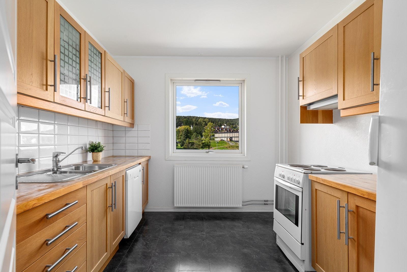 Godt vedlikeholdt kjøkken med innredning bestående av over- og underskap samt skuffer Galleribilde