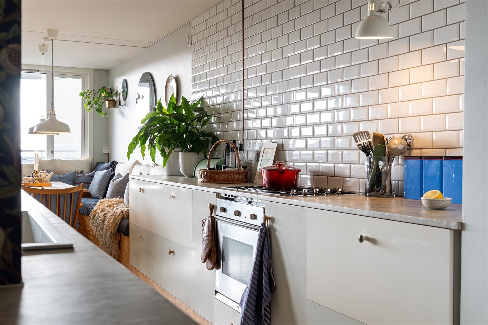 Stilig kjøkken med hvite glatte fronter med ulike håndtak, gasstopp og fin flislagt vegg som går helt til taket. Galleribilde