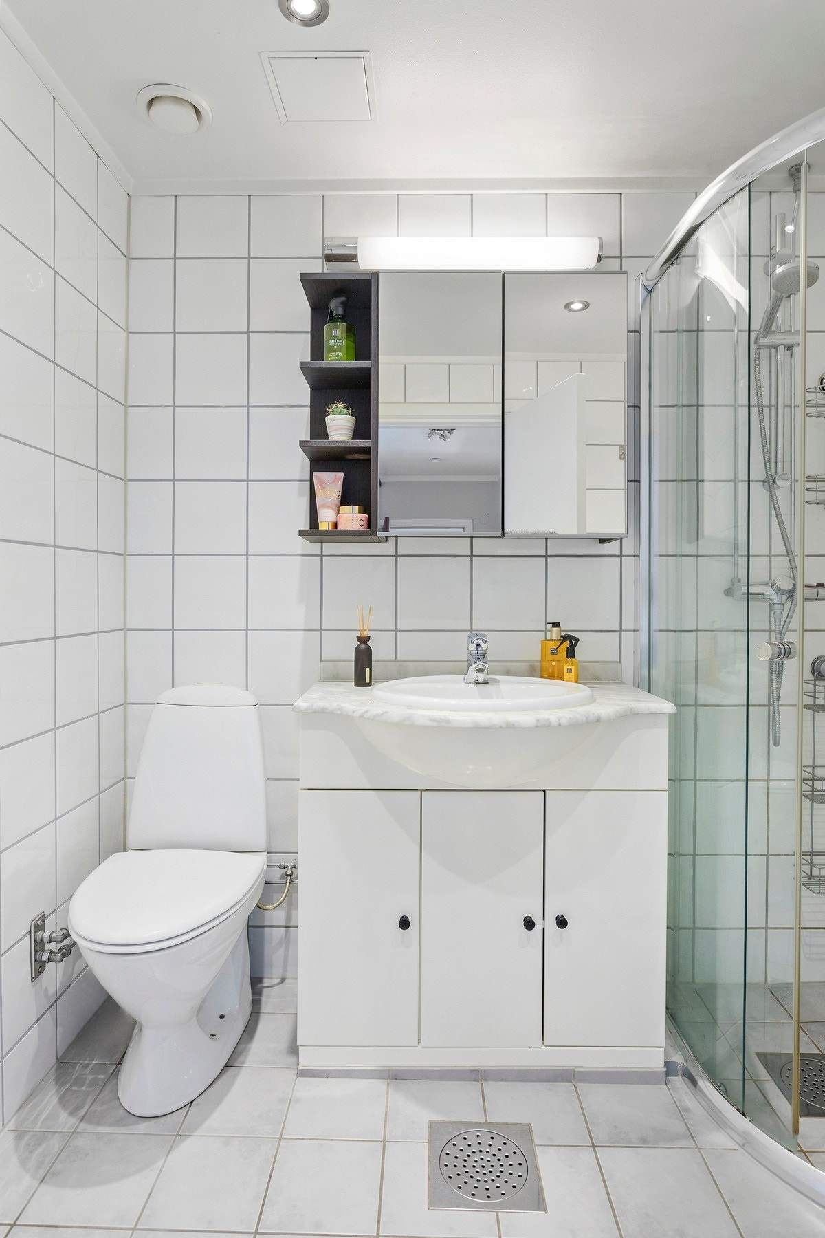 Innredningen består av servant på underskap samt speilskap og hyller på overside. Videre er det dusjhjørne med skyvedører og gulvstående toalett. Galleribilde