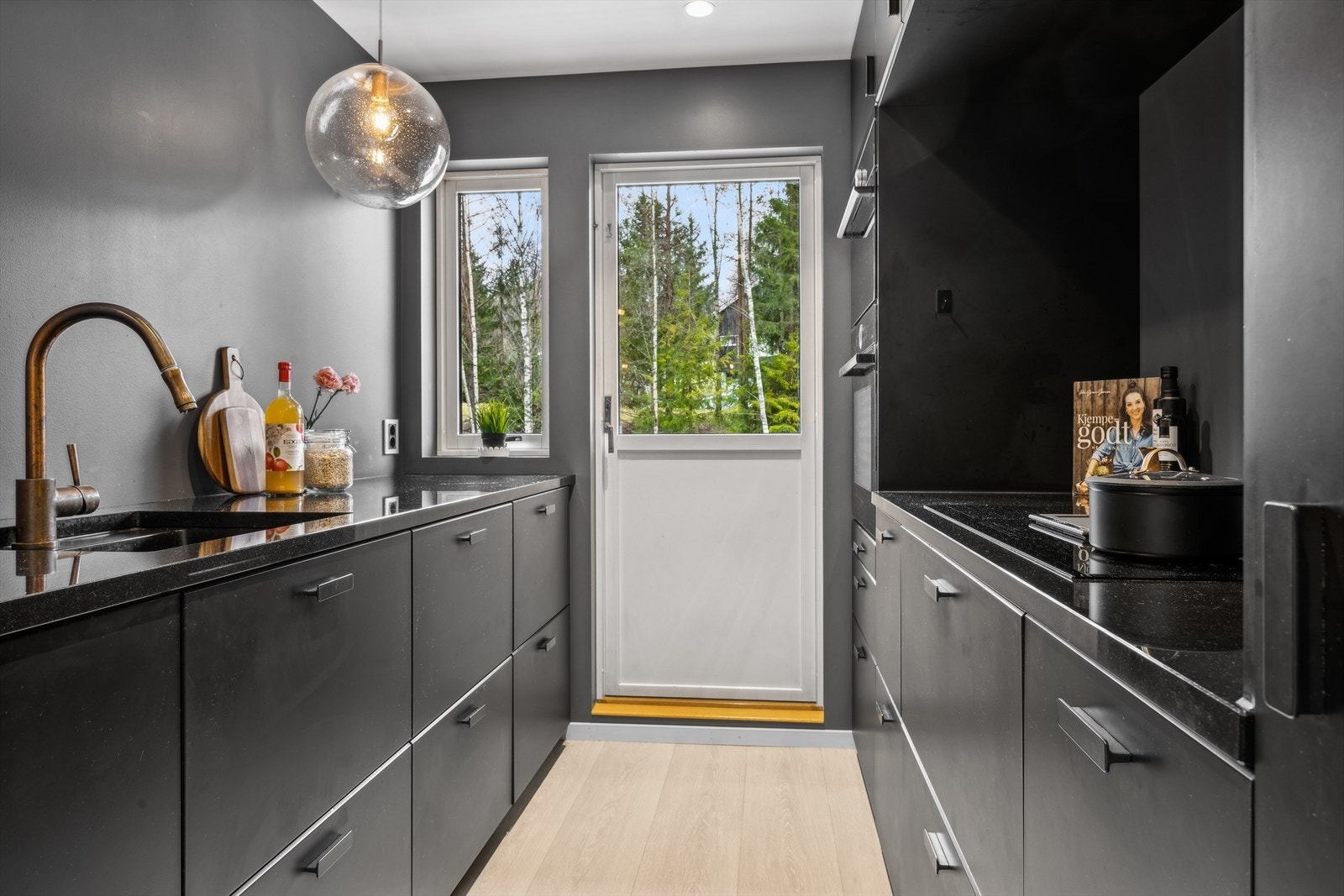 Kjøkkenet har mørke farger og detaljer i kobber messing. Galleribilde