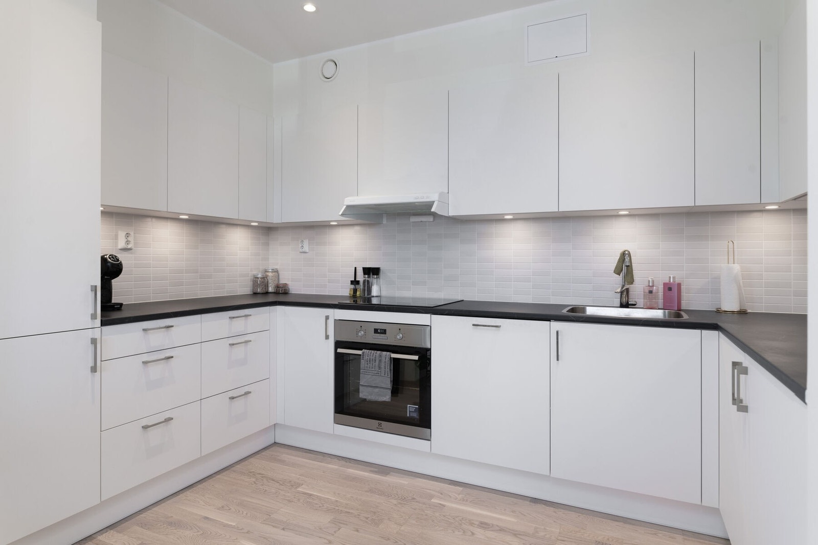 Lyst og pent kjøkken med mye skap- og benkeplass. Det er slette fronter og benkeplate av laminat. Galleribilde