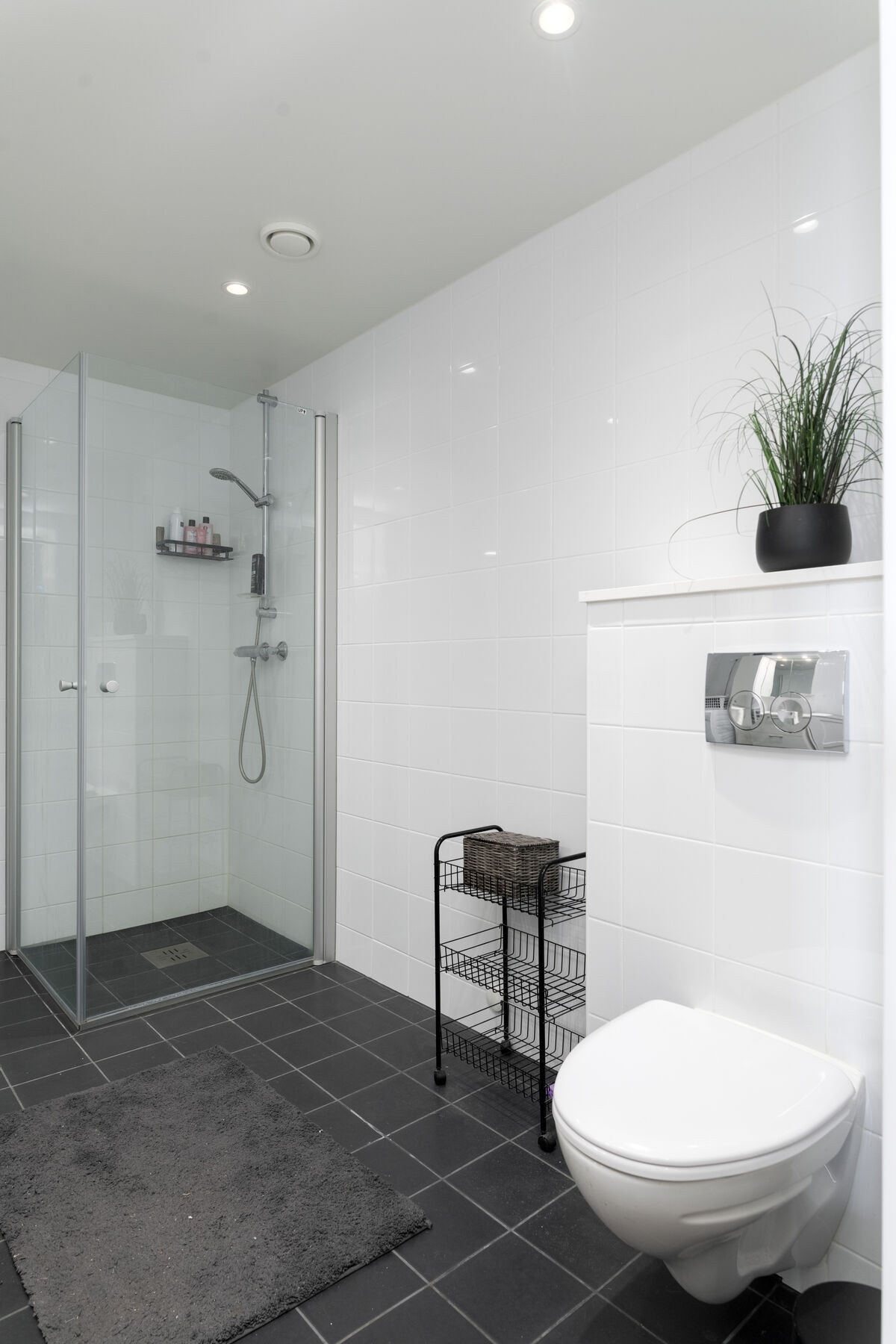 Badet har veggmontert wc, dusjhjørne, servant på innredning med speilskap og opplegg for vaskemaskin. Galleribilde