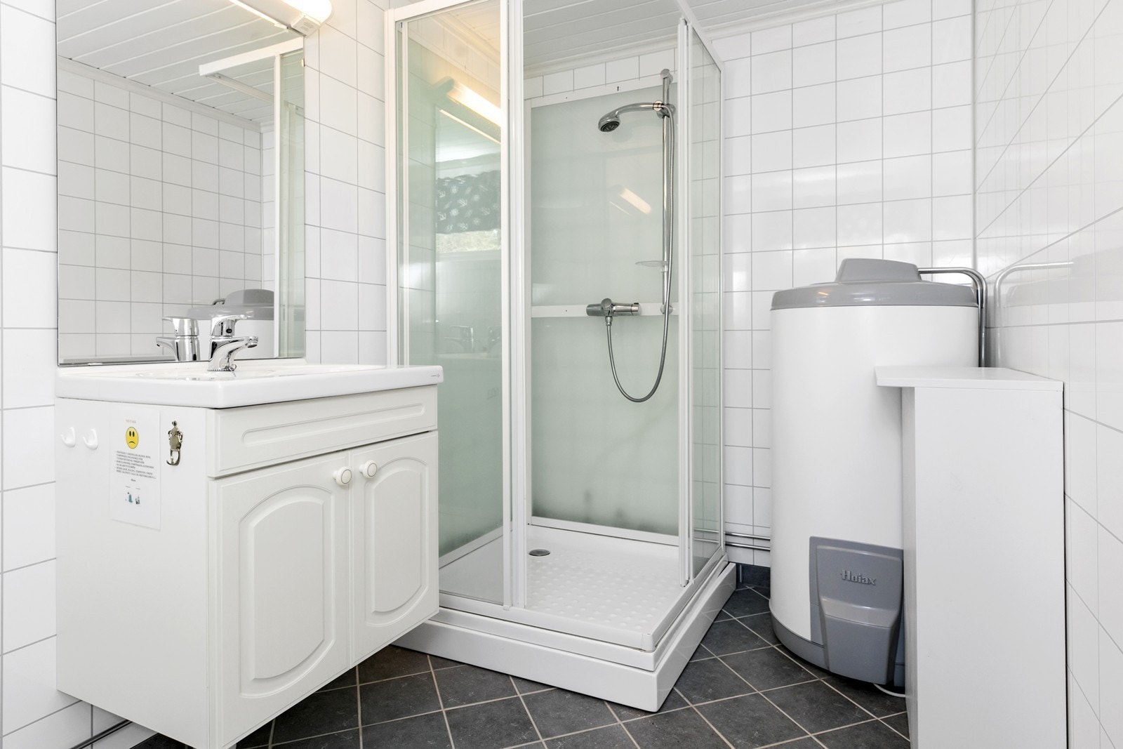 Bad har dusjkabinett, wc, servantinnredning og opplegg for vaskemaskin Galleribilde