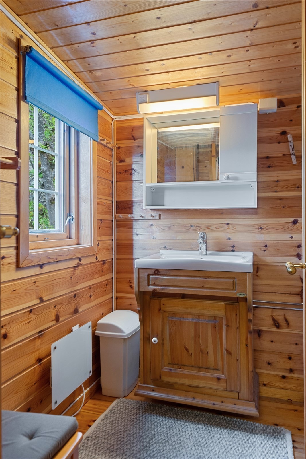 Badet har enkel innredning med vask og speilhylle på vegg og wc i eget rom. Galleribilde