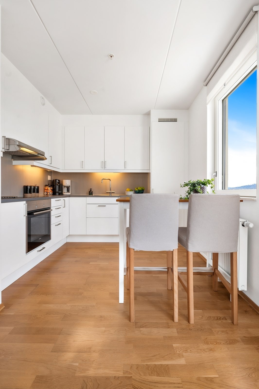 Dette moderne kjøkkenet har en elegant innredning fra Marbodal med kritthvite fronter fra 2017 og rustfrie stålhåndtak. Galleribilde