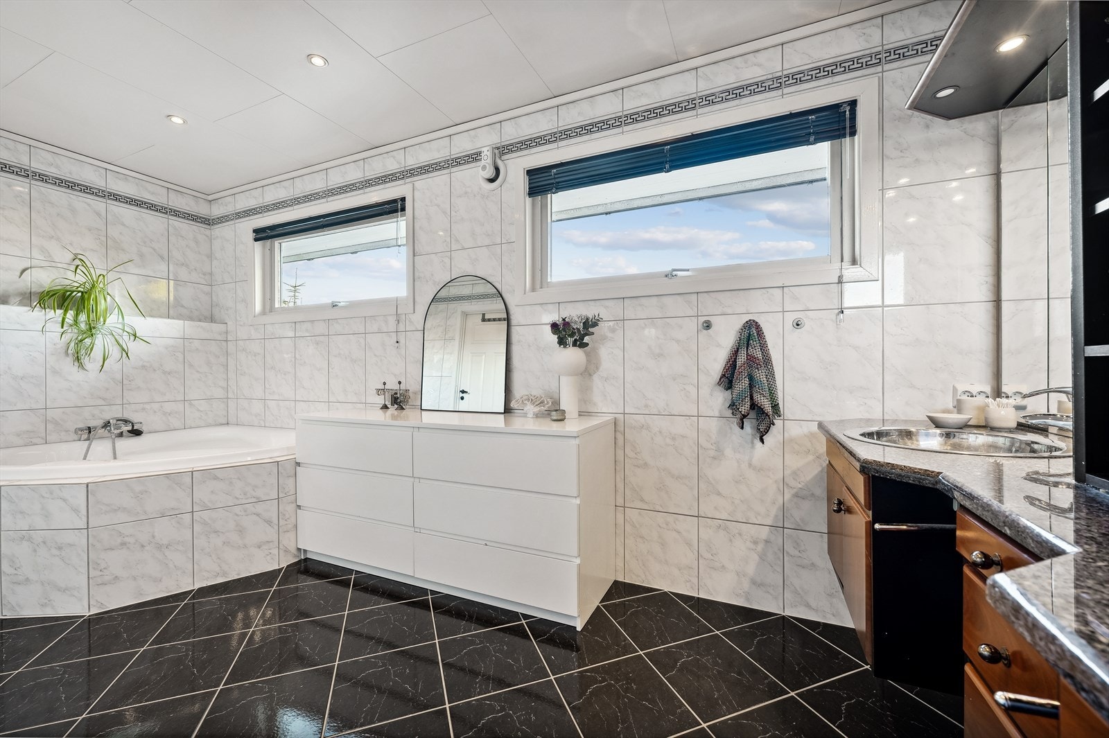 Badet i 1. etasje er flislagt med varmekabler i gulv og downlights i himling. Badet er innredet med vegghengt toalett, badekar, dobbel vask, skapservant m/integrert radio og dusjhjørne. Galleribilde