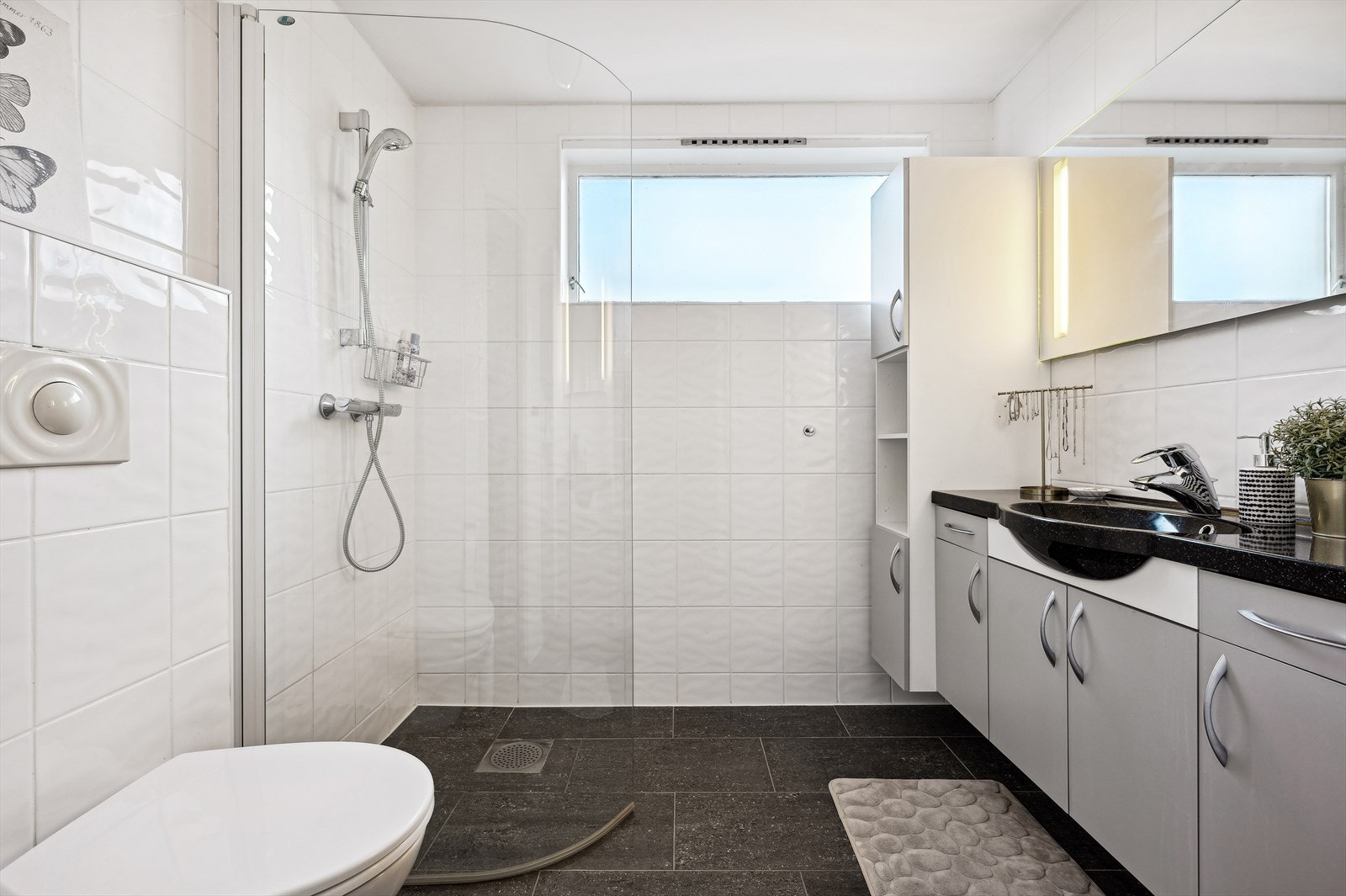 Tidløst flislagt bad i underetasjen fra 2007. Badet er utstyrt med dusjnisje, vask i seksjon og vegghengt toalett. Det er varmekabler i gulv. Galleribilde