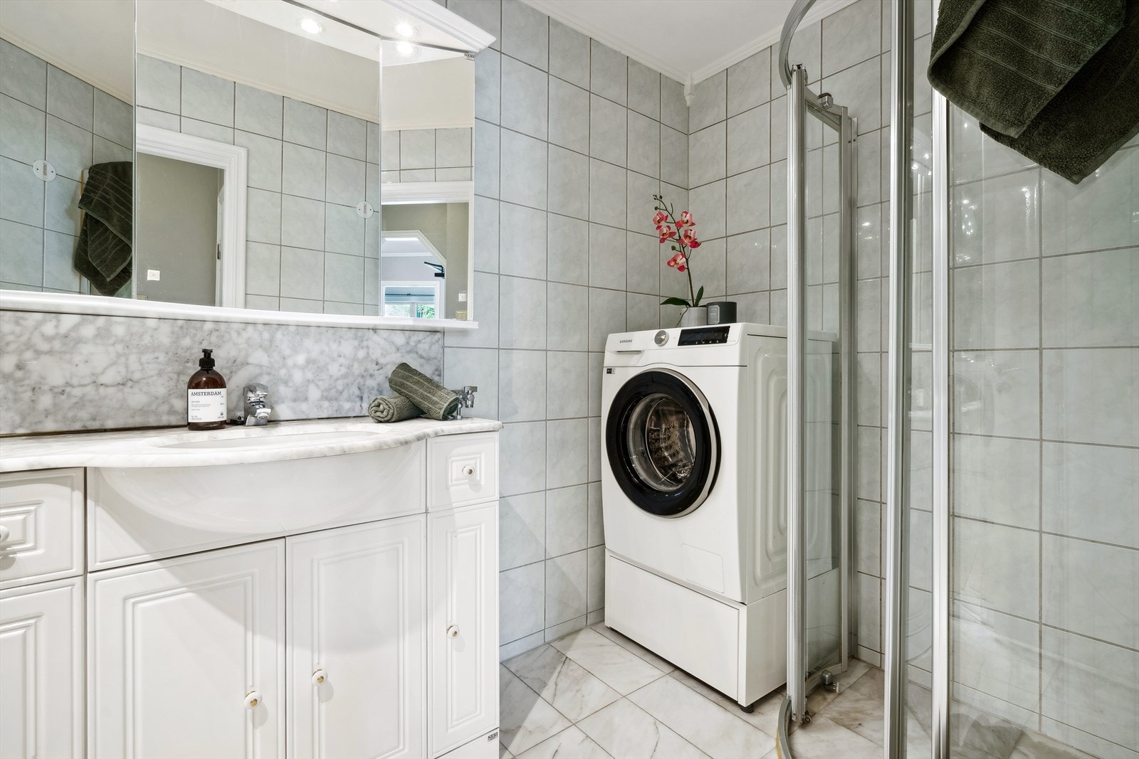 Pent bad/ vaskerom. Badet er utstyrt med lyse fliser på gulv, lyse fliser på vegg og dusj hjørnet med skyvedører Galleribilde