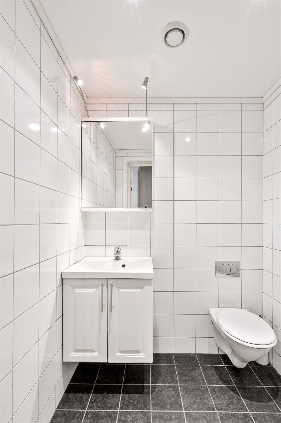 Lyst og praktisk baderom med servant med skap og vegghengt toalett Galleribilde