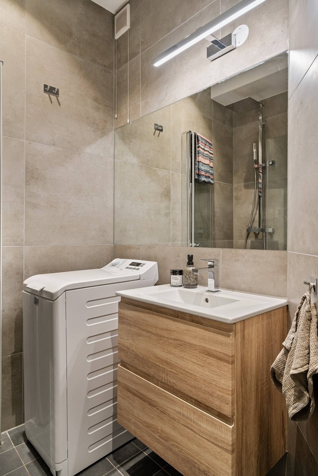 Rommet er videre innredet med vegghengt servantinnredning med skuffer og ovenpåliggende servant samt vegghengt speil og lys. Galleribilde