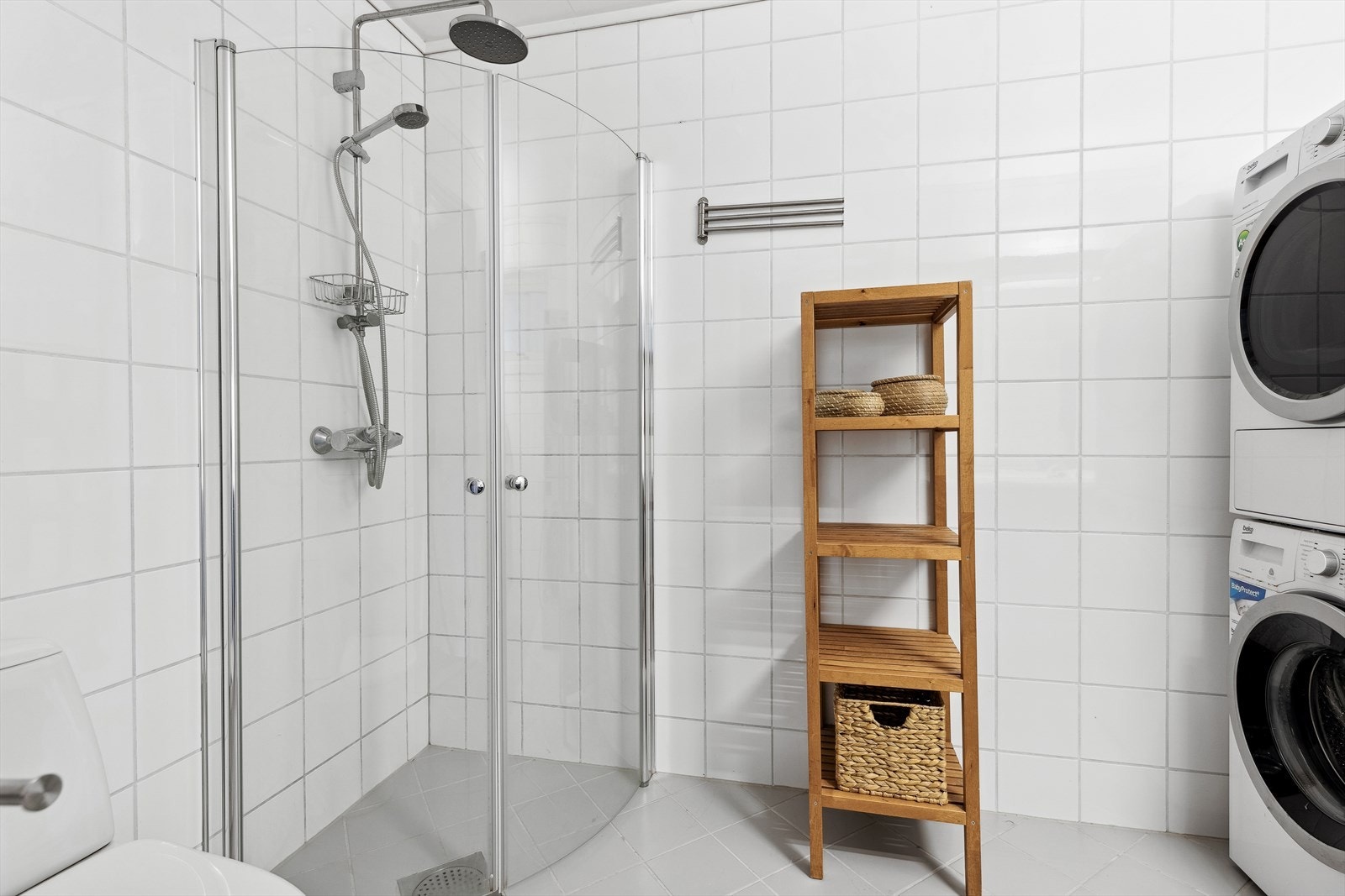 Rommet har mørk innredning med servant, overskap, speil med belysning, toalett, dusjhjørne med innfellbare glassvegger, regnfallsdusj og opplegg for vaskemaskin og tørketrommel Galleribilde