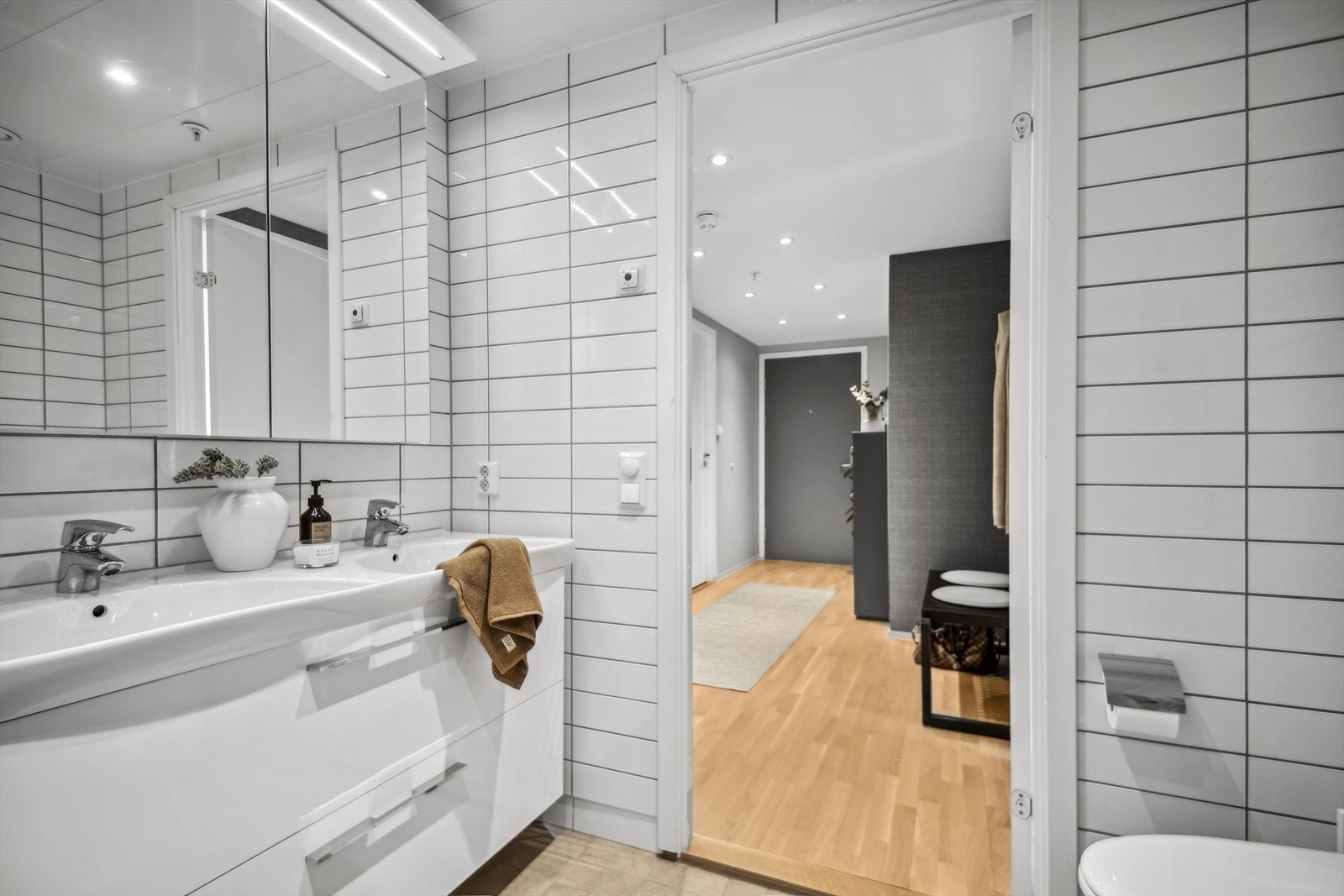 Lyst og flislagt baderom med dobbeltservant og overhengt speilskap. Galleribilde