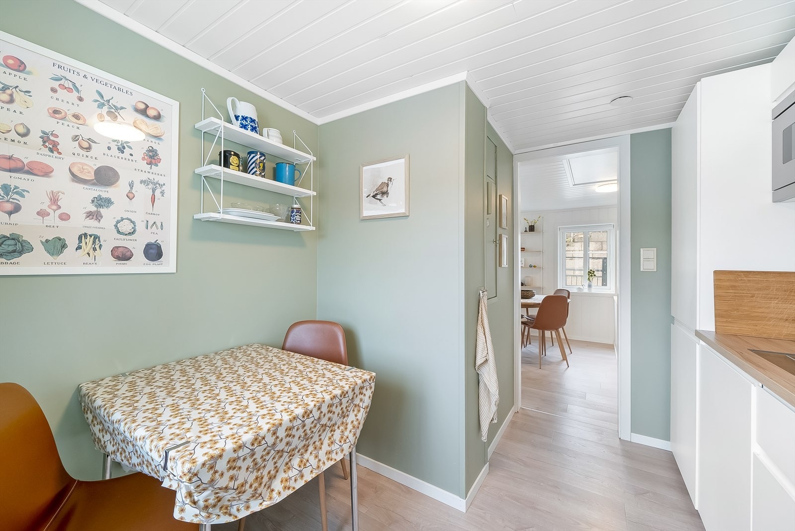 Pent kjøkken malt opp i en lun grønnfarge med plass til et lite kjøkkenbord hvor morgenkaffen kan nytes. Galleribilde