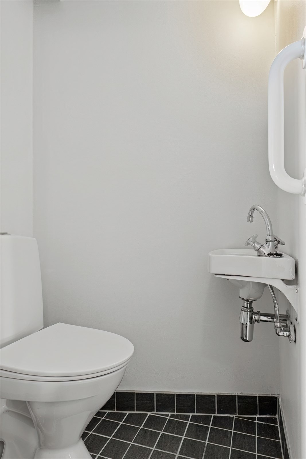 Toalettrom har fliser på gulv og er innredet med toalett og enkel servant. Galleribilde