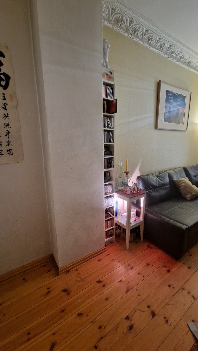 Sofa, tynn hylle. sidebord. Til venstre kommer det et stort klesskap, samt en åpen hylleseksjon med 5 hyller. Galleribilde