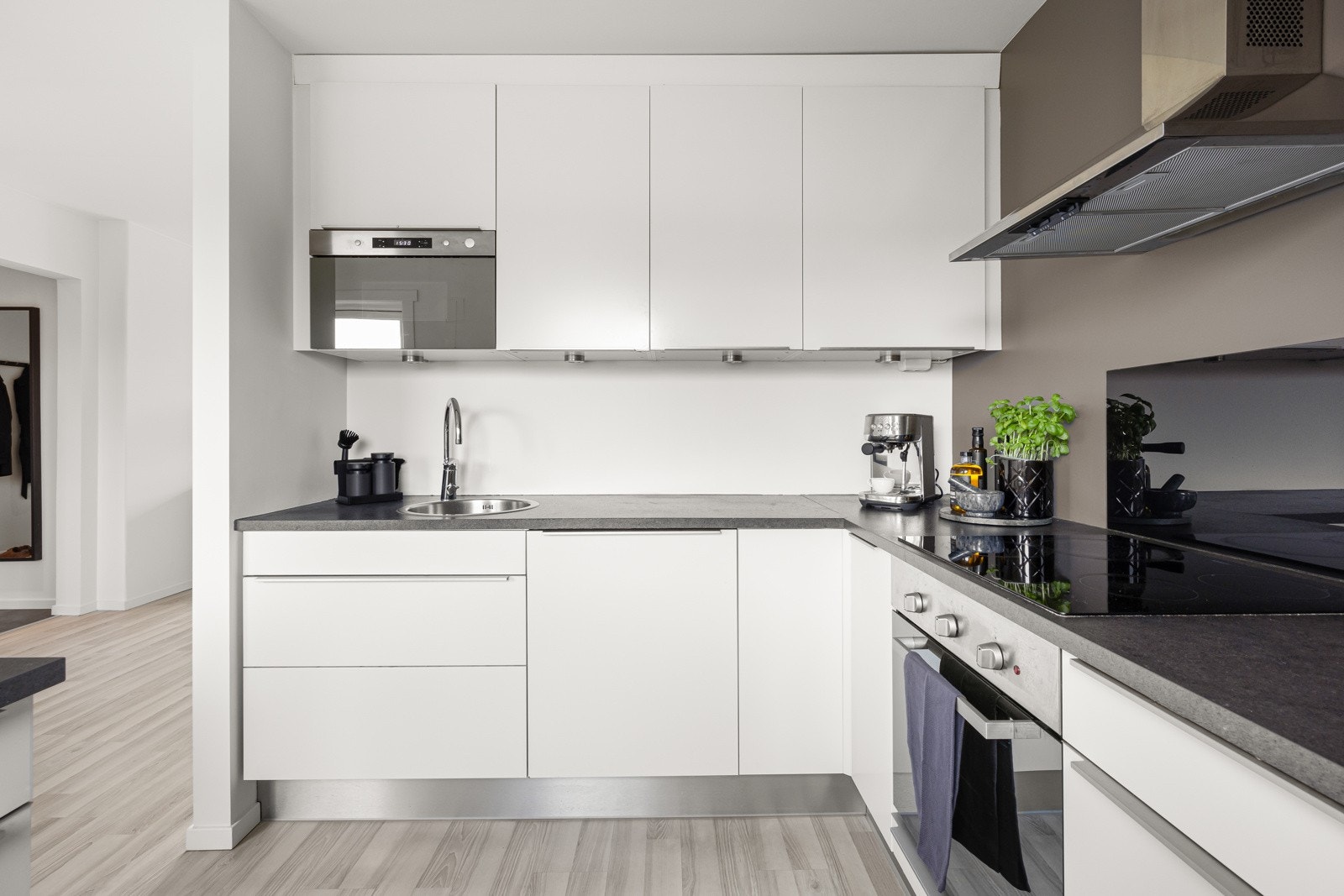 Slette, hvite fronter og belysning over laminat benkeplate. Galleribilde