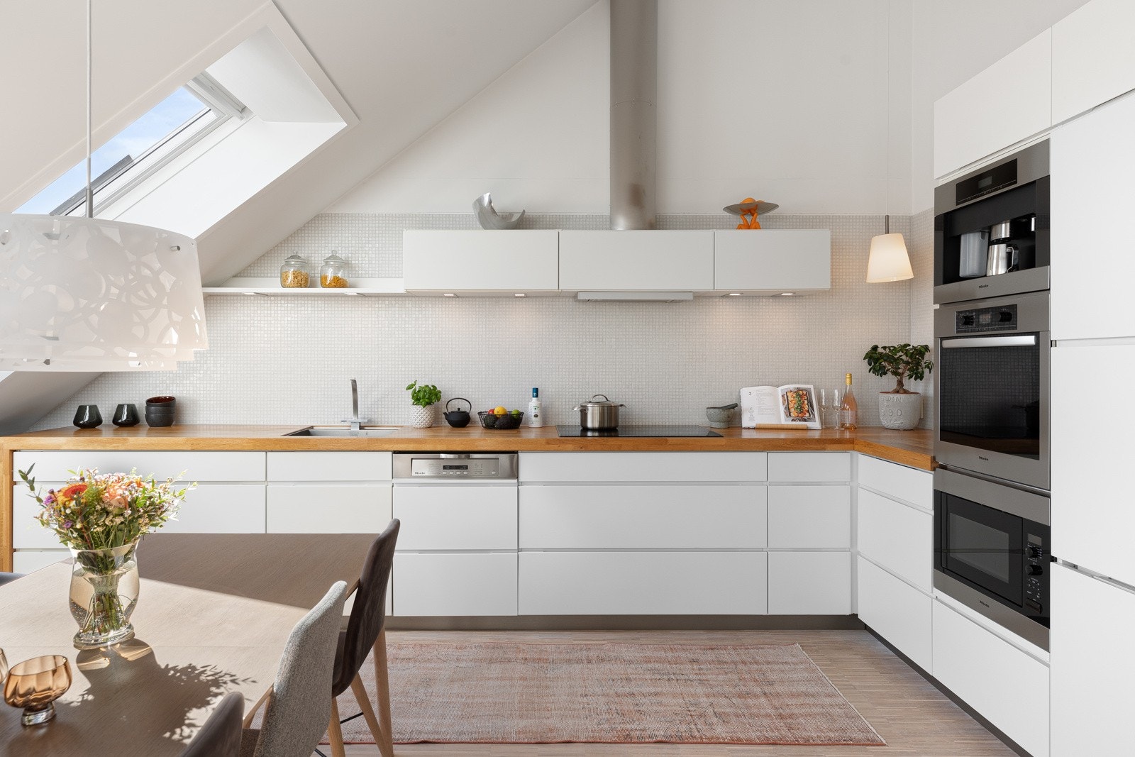 Integrerte hvitevarer fra Miele/Siemens som oppvaskmaskin, kjøl/frys, og stekeovn, kaffemaskin og micro i høyskap samt induksjonsplatetopp. Integrert avtrekksvifte i overskap Galleribilde