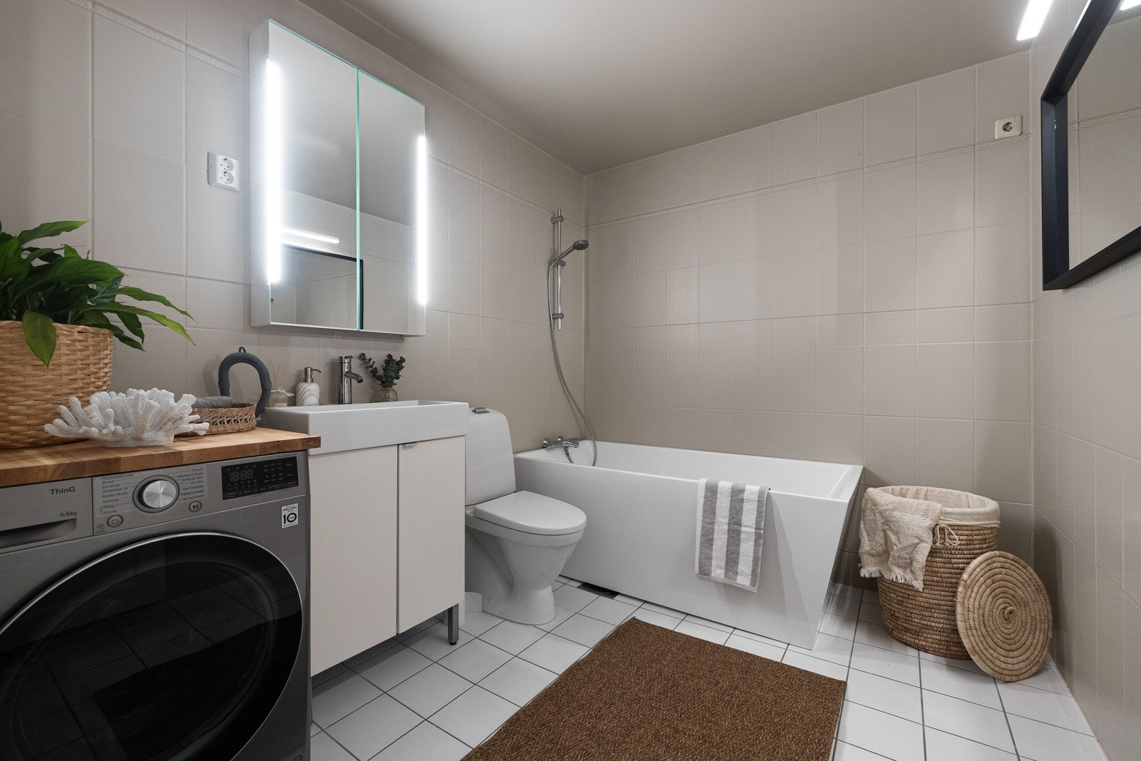 Hovedbad med badekar og opplegg for vaskemaskin med praktisk arbeidsbenk over. Galleribilde