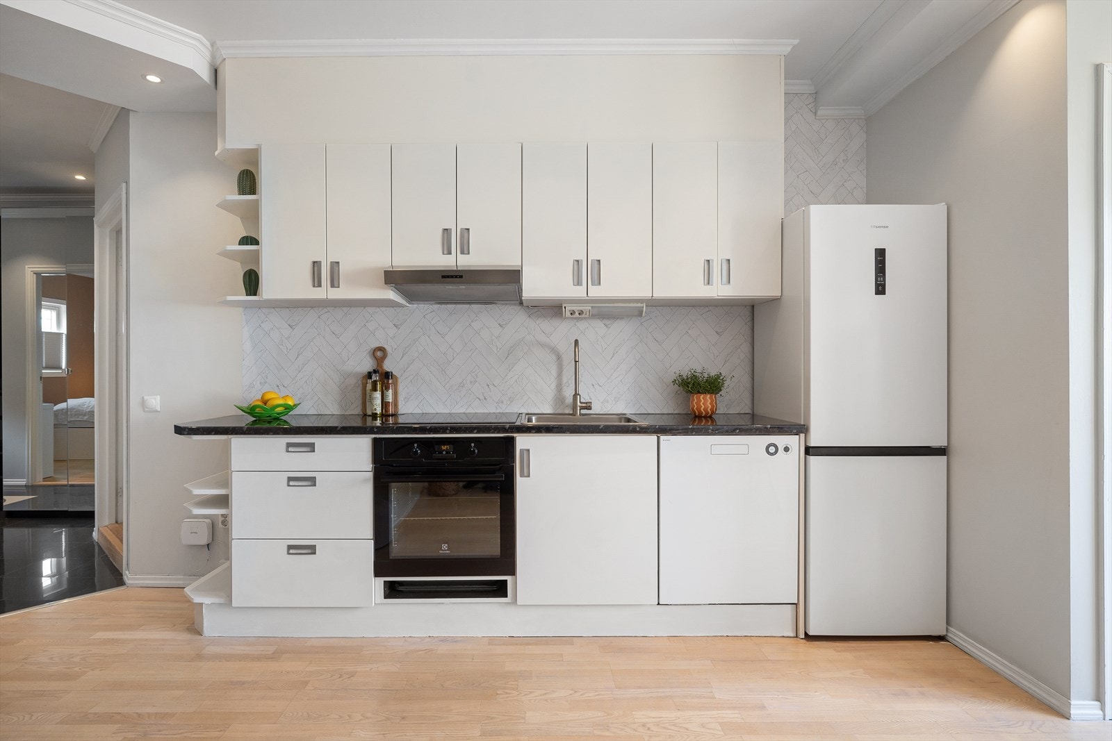 Lys innredning med malte fronter, kontaktplast på vegg over kjøkkenbenk og benkeplate i laminat. Galleribilde