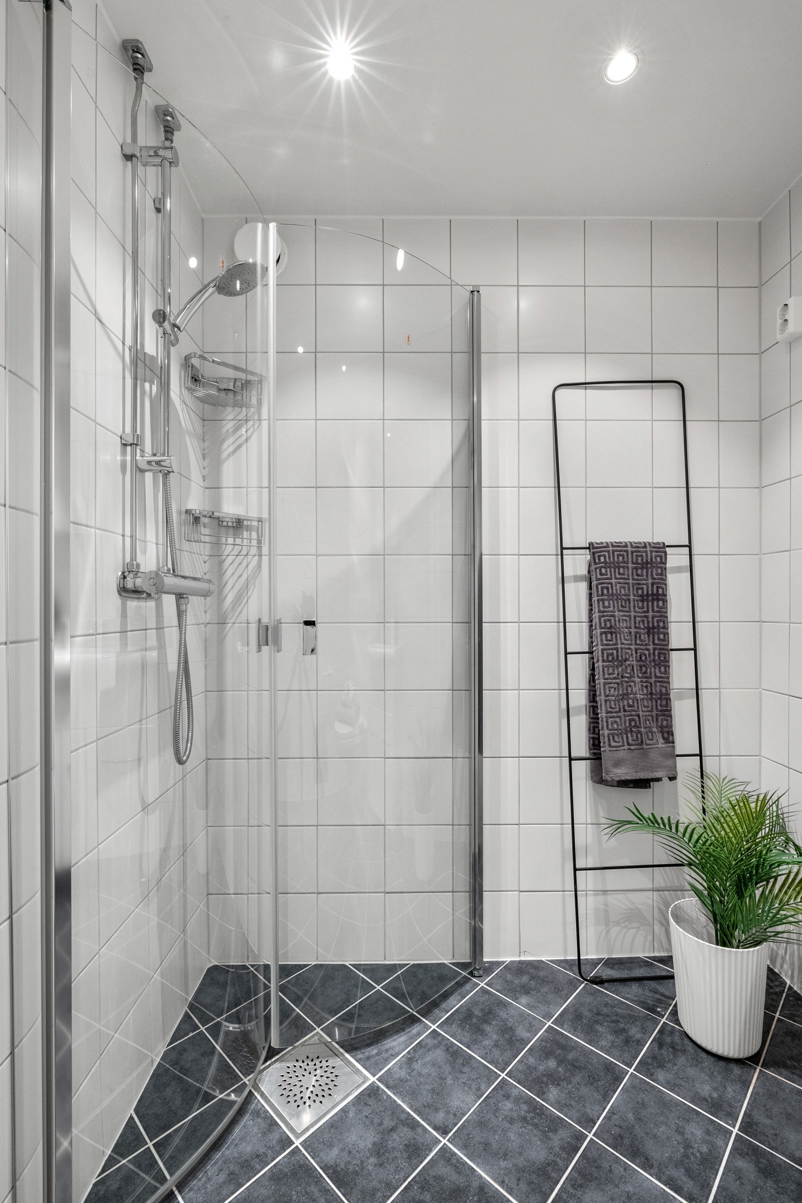 Badet inneholder servantskap med glatte fronter og heldekkende servant, veggmontert klosett, og dusjhjørne med svingdører i glass og dusjutstyr. Det er opplegg for vaskemaskin. Galleribilde