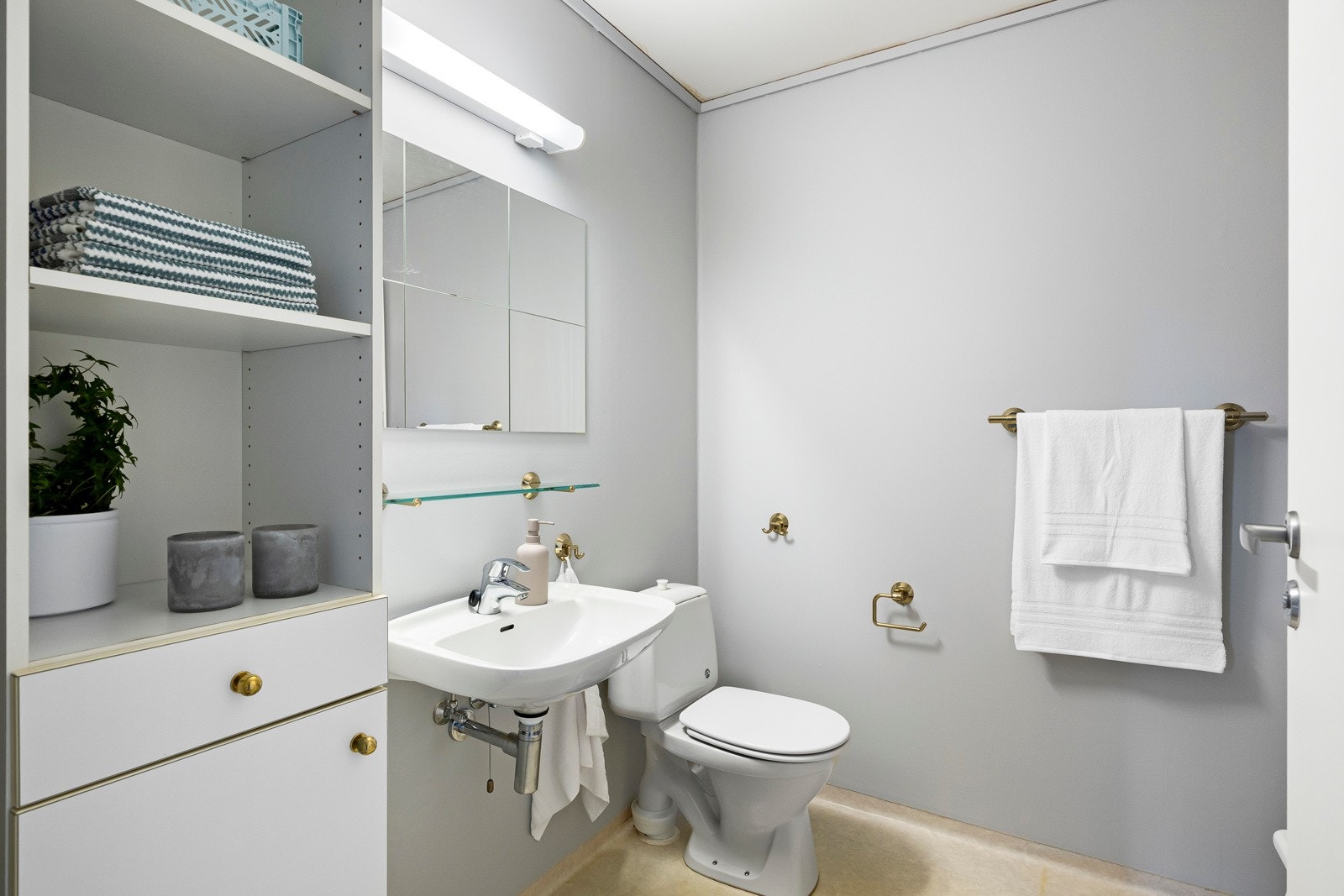 Ved soverommene i andre etasje er det et pent og praktisk bad med lysegrå vegger og beige belegg på gulv med sluk. Galleribilde