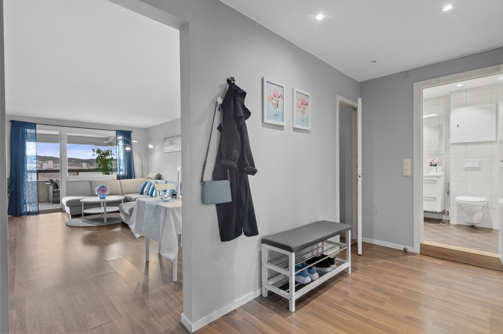 Leilighetens entrè/gang er både lys og romlig med delvis åpening mot stuen. Det kan innredes med skohylle, knagger, skjenk eller kommode Galleribilde