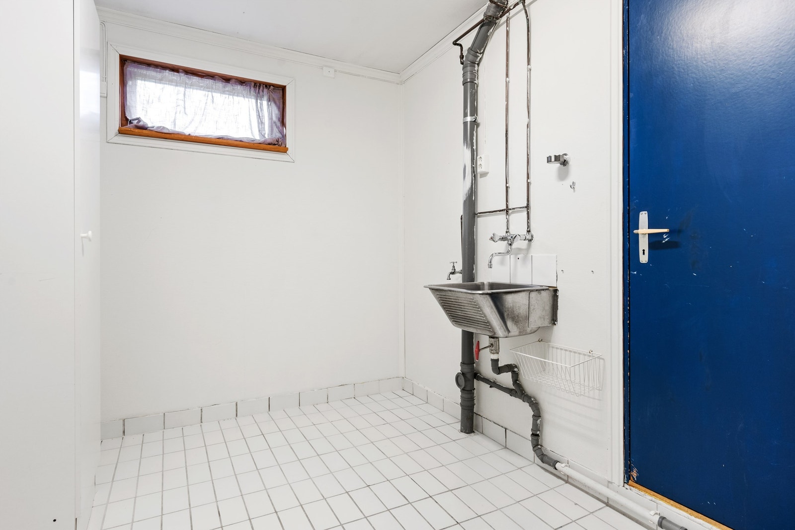 Vaskerommet har flislagt gulv med varmekabler, malt strie på vegger og opplegg for vaskemaskin Galleribilde