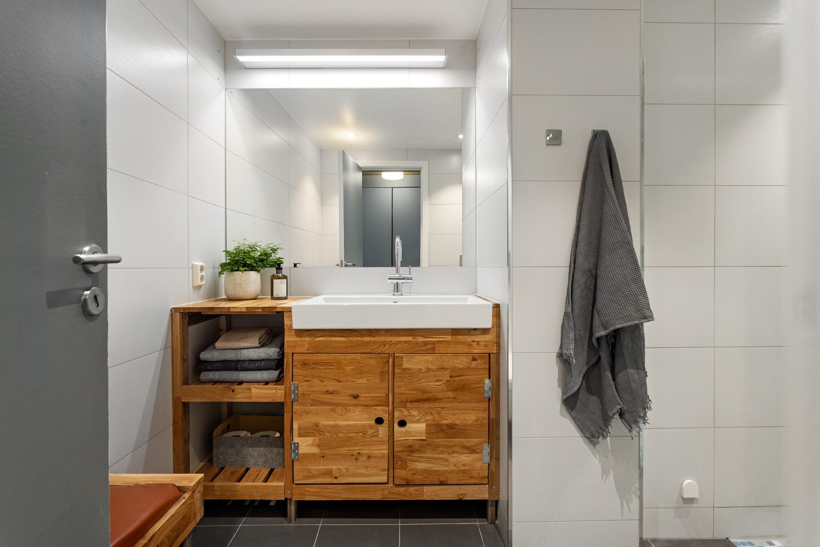Leiligheten har et lyst og moderne flislagt baderom som ble pusset opp i 2014. Praktisk baderomsinnredning med nedfelt servant og stort speil med belysning over. Galleribilde