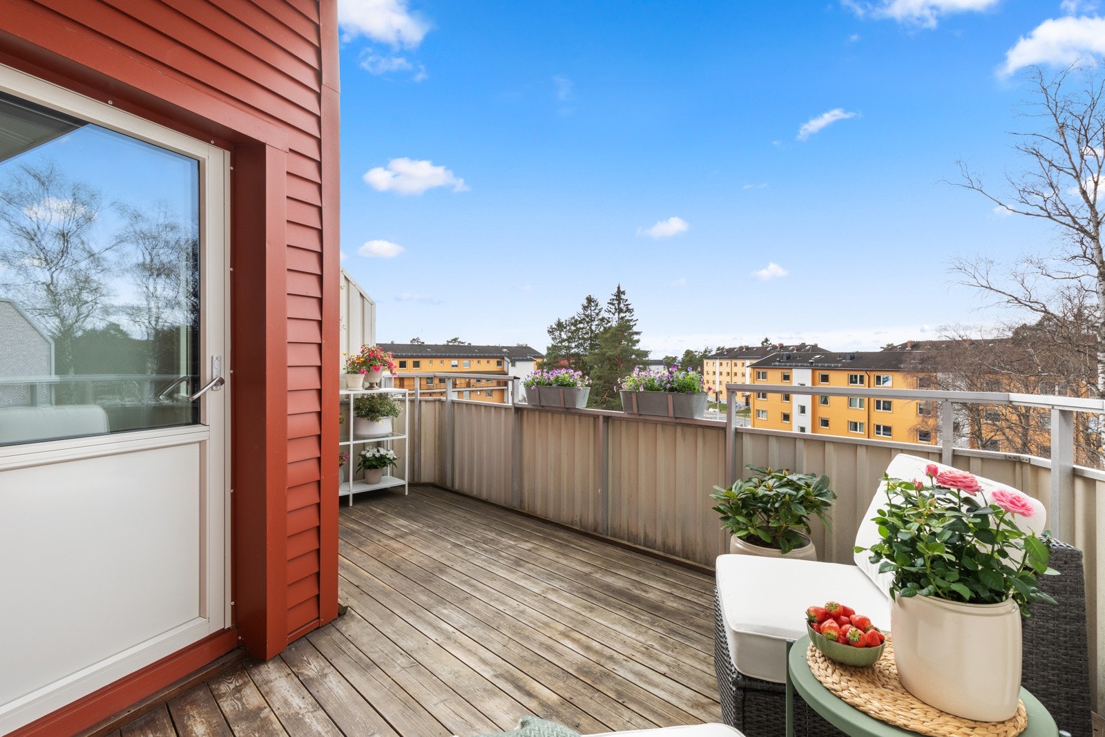 En vestvendt og solrik balkong med tregulv som dekke. Galleribilde