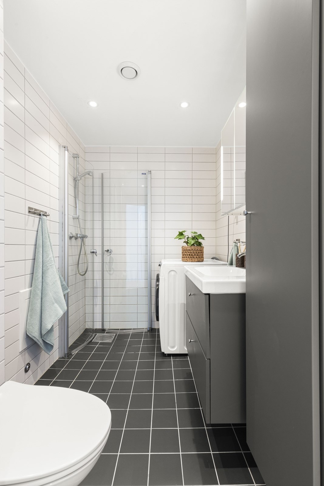 Badet er utstyrt med et veggmontert toalett, en servantinnredning, et dusjhjørne med glassdører samt opplegg for vaskemaskin. Badet ble fornyet med ny innredning i 2021. Galleribilde
