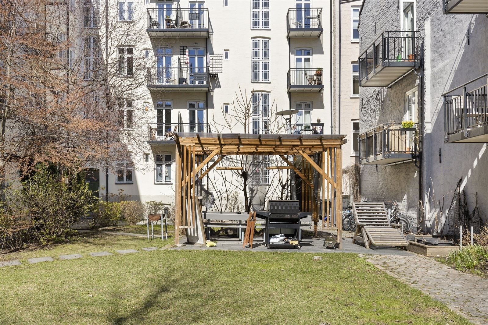 Sittegrupper, grill, sykkelparkering og diverse beplantning i bakgården. Galleribilde