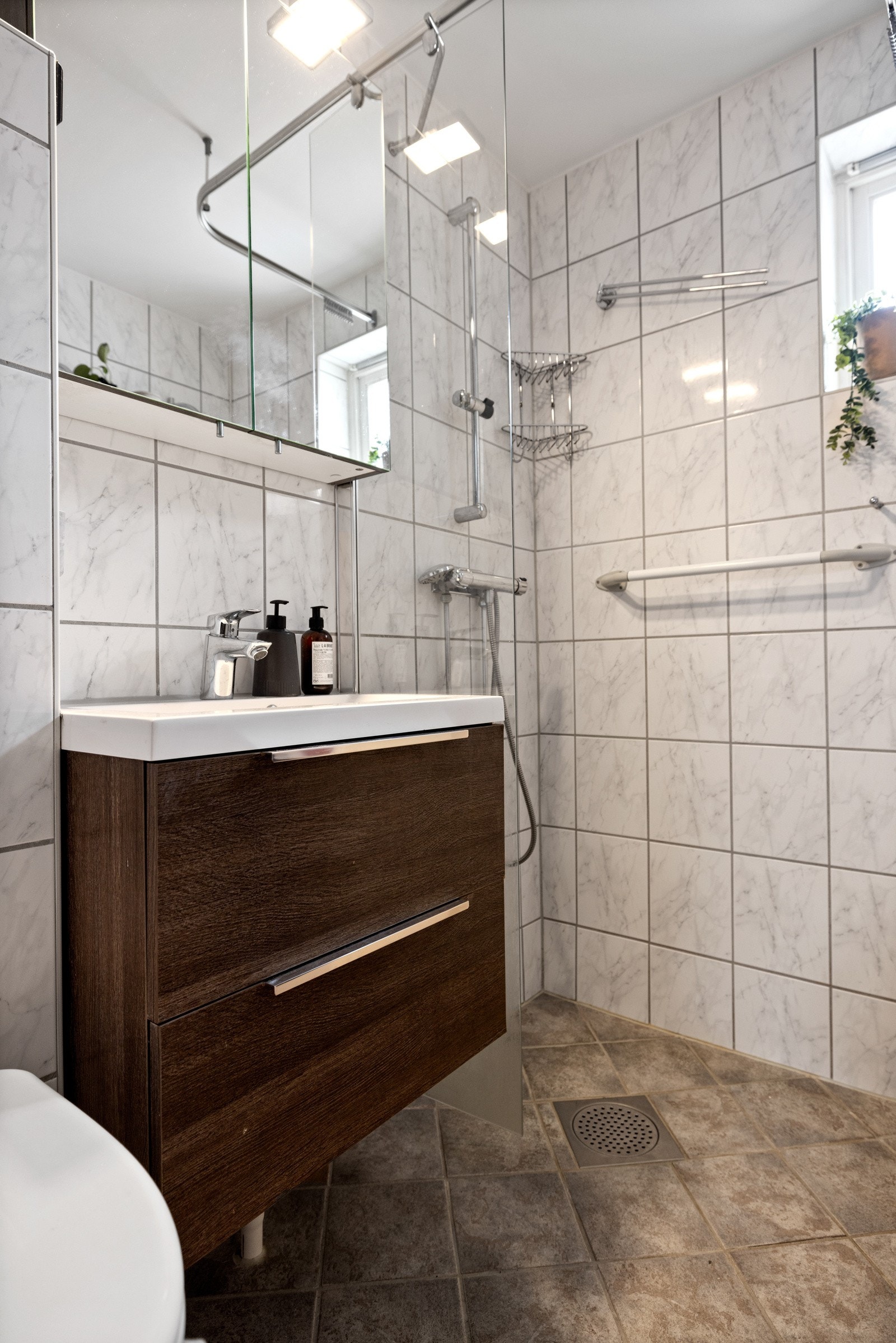 Innredningen består av en heldekkende servant på nøttebrun skuffeseksjon, matchende høyskap og speilskap over servanten. Galleribilde