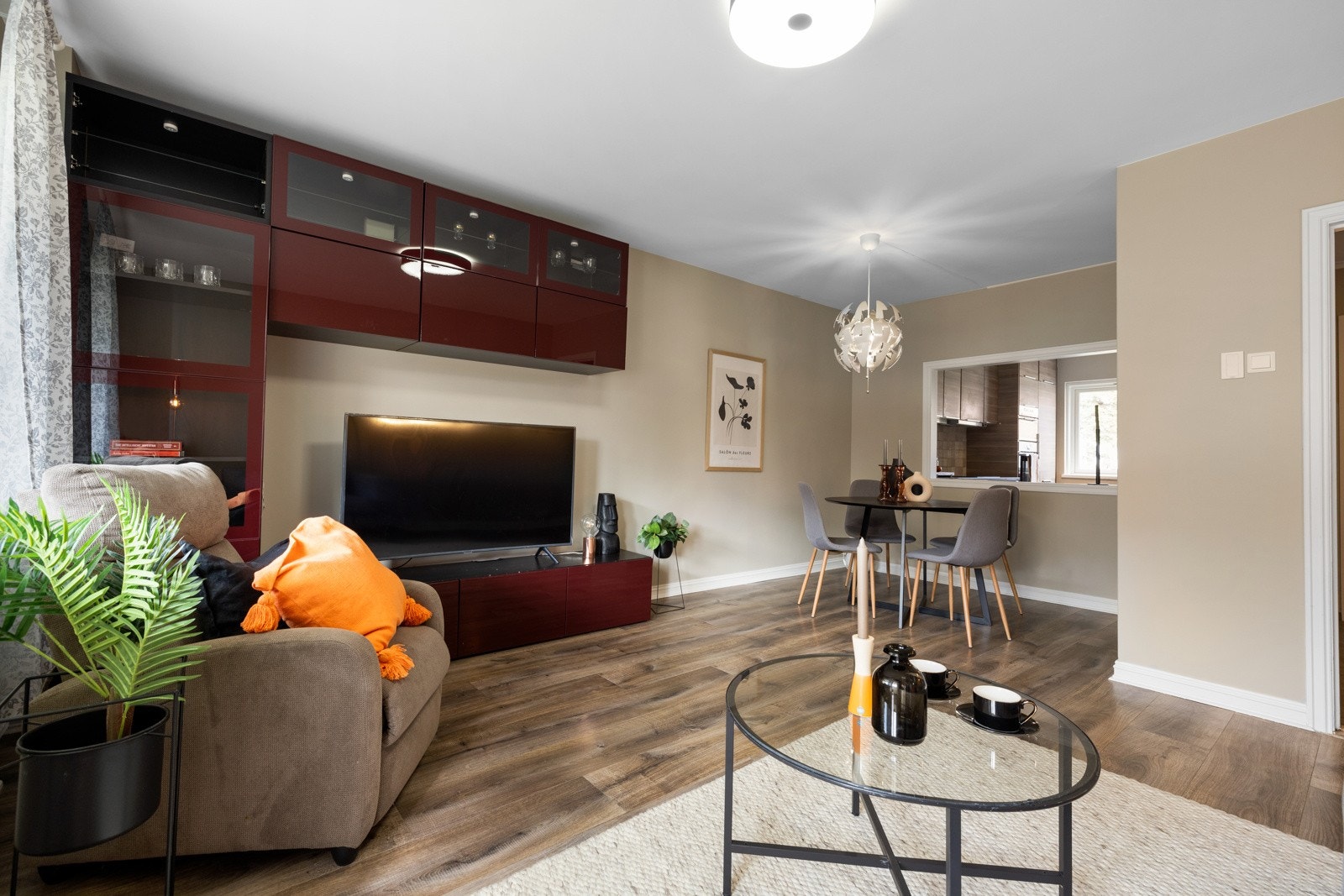 Stuen har beige veggflater, listefritt tak, gulv i eikelaminat og en stor vindusåpning mot kjøkkenet. Galleribilde