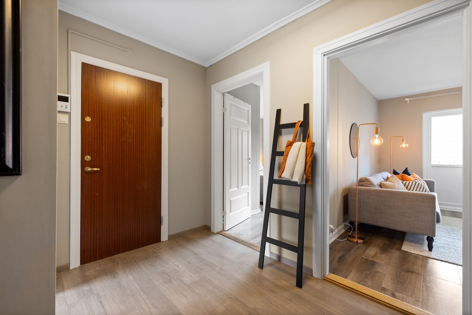 Entreen har vegger malt i en dyp beigefarge, laminatgulv og glatt, hvitmalt himling. Galleribilde