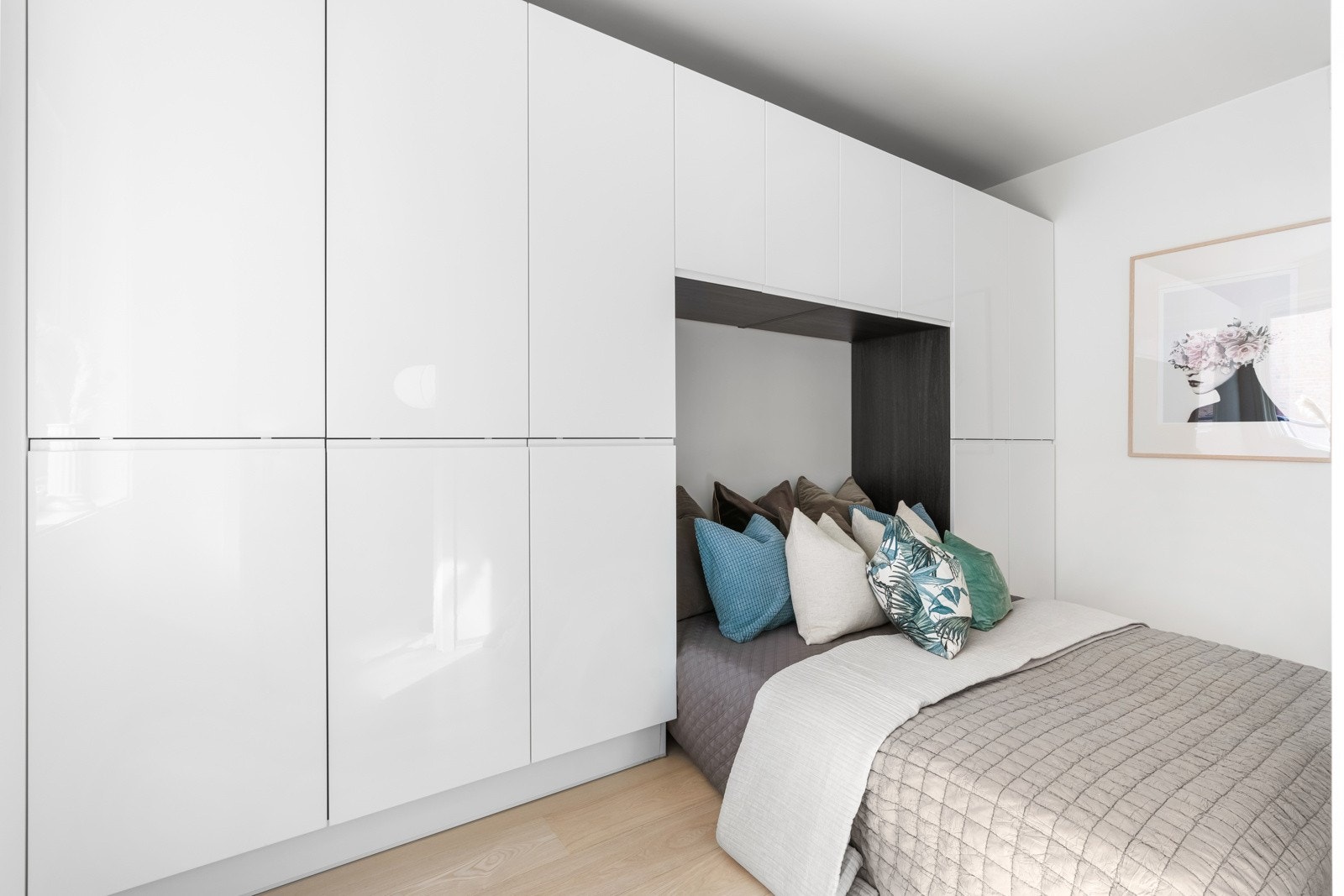 Sengeplassen rammes inn av flere garderobeskap og veggskap som gir godt med oppbevaring til klær. Galleribilde