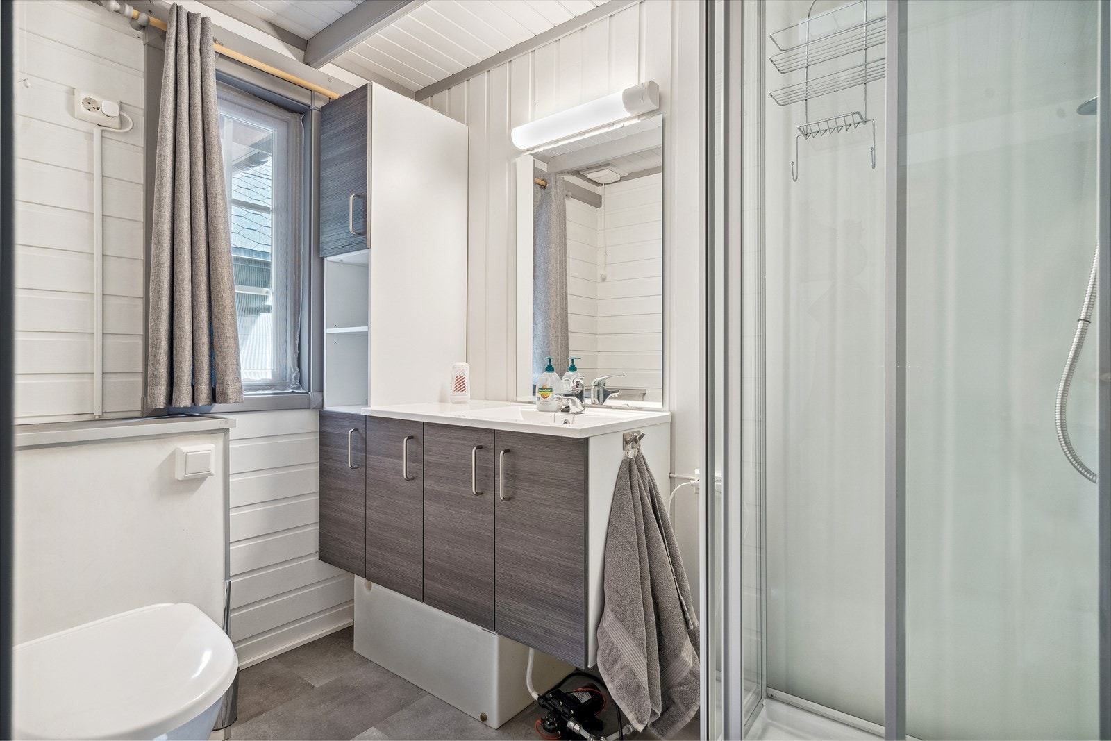 Komplett baderom med dusjkabinett, klosett og moderne servant med servantskap. Galleribilde