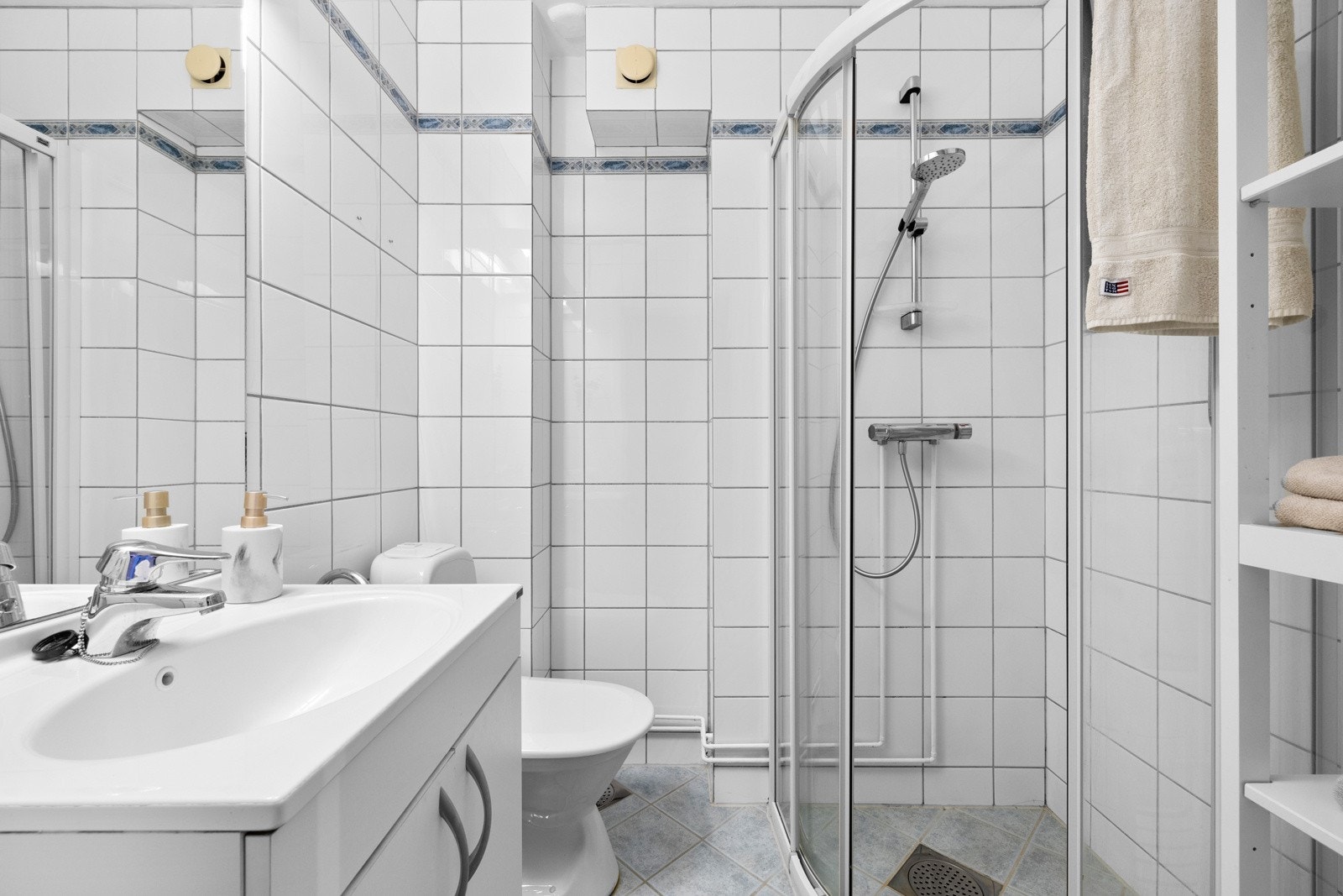 Badet inneholder dusjhjørne med skyvedører, wc, servantskap og speil på vegg Galleribilde