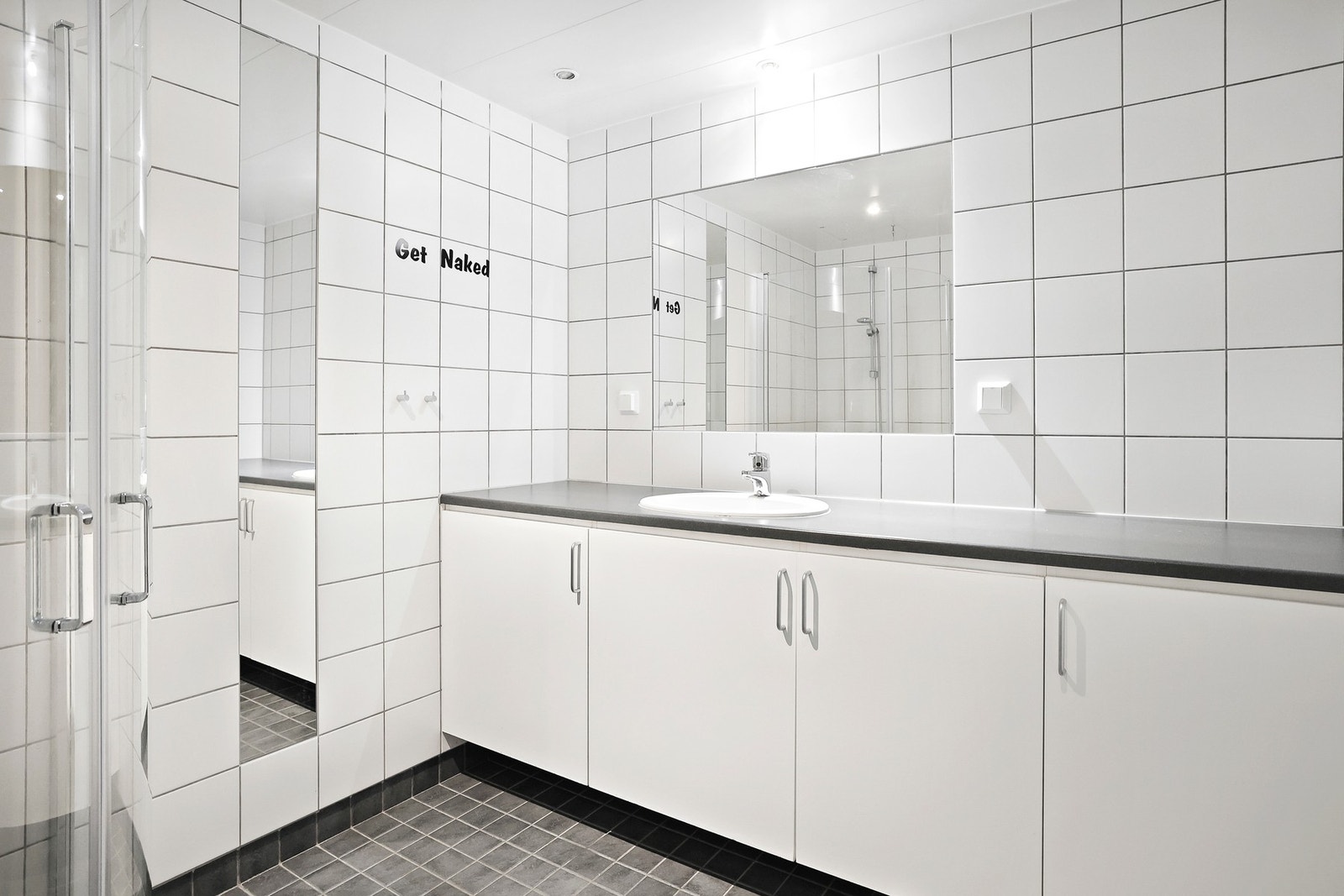 Badet har en innredning med plass til oppbevaring, veggmontert toalett og dusjhjørne. Galleribilde