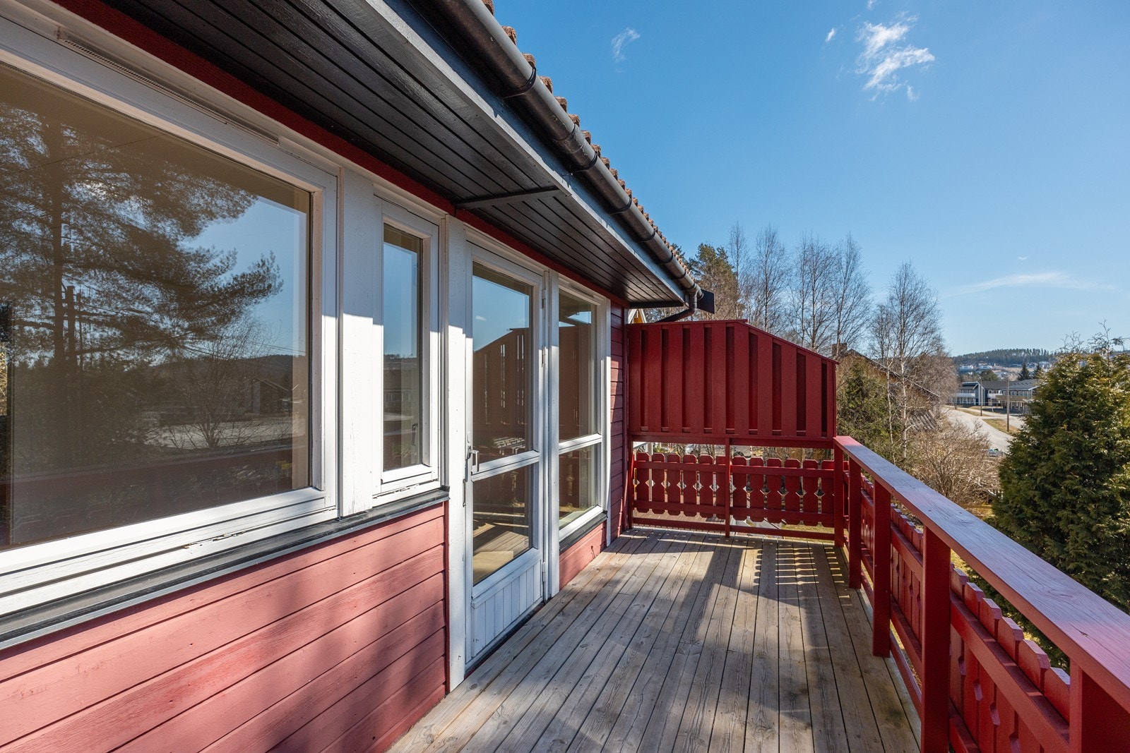 Balkongen har et lite overbygg, malt rekkverk i front og levegg på en side Galleribilde