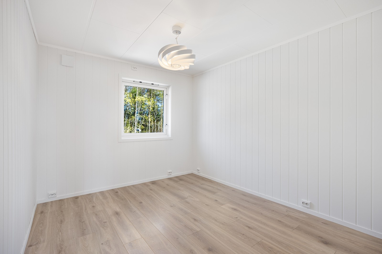 Soverommet er lyst og trivelig med laminatgulv, dus farge på veggpanel og vindu på endeveggen Galleribilde