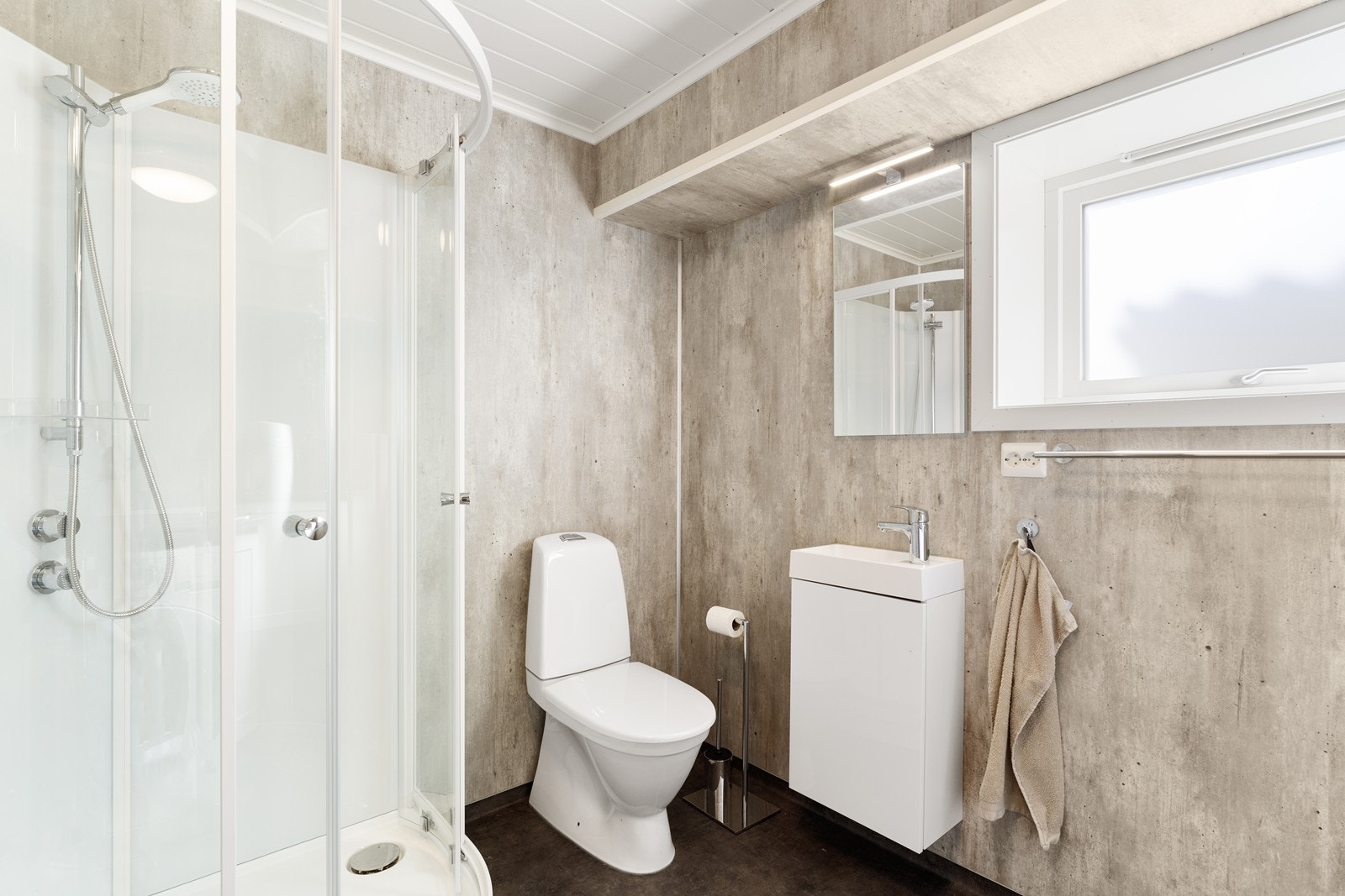 Badet er videre innredet med dusjkabinett, gulvstående toalett og innredning med vask og et greps blandebatteri Galleribilde