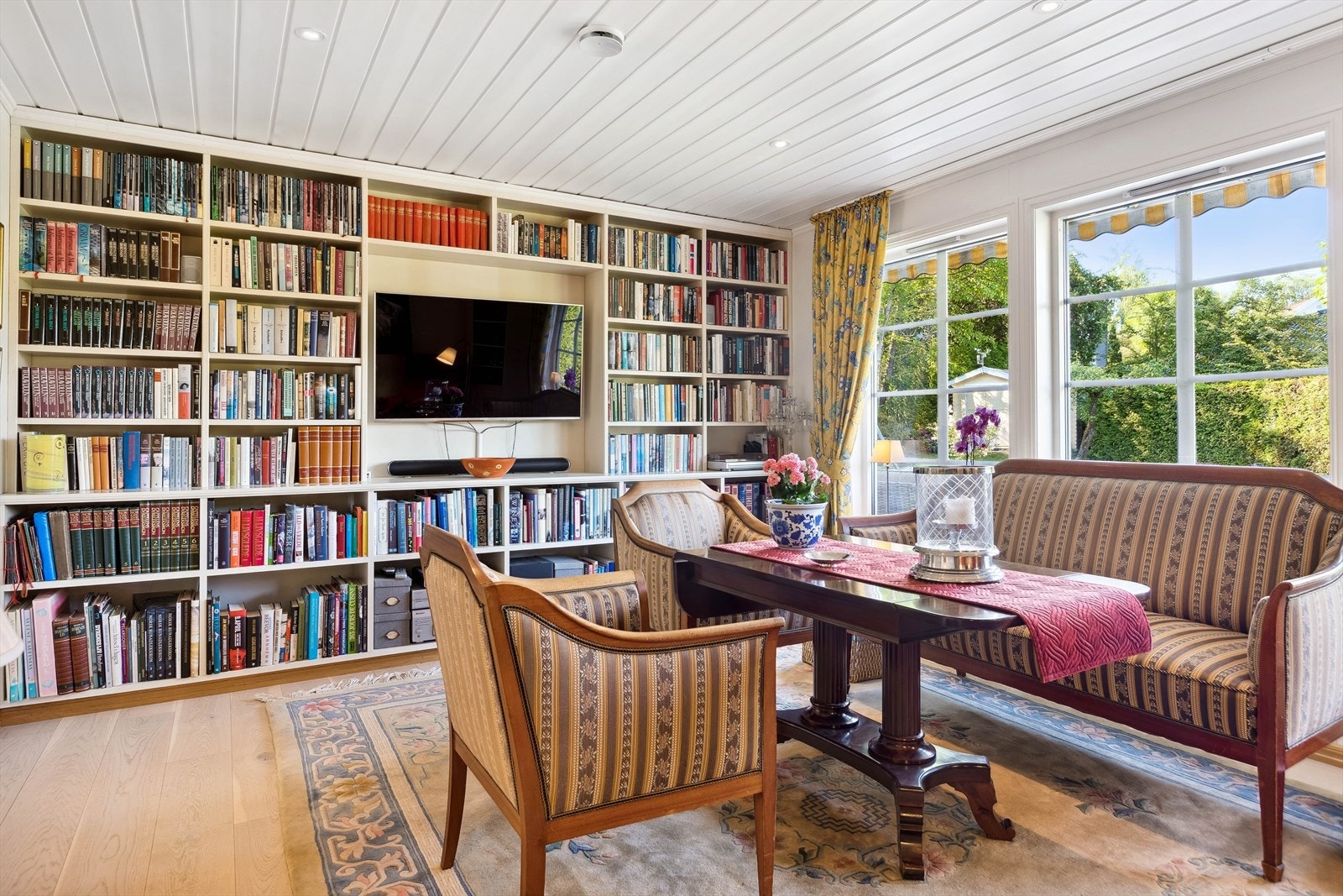 Koselig bibliotek og TV-stue med store vinduer ut mot haven. Galleribilde