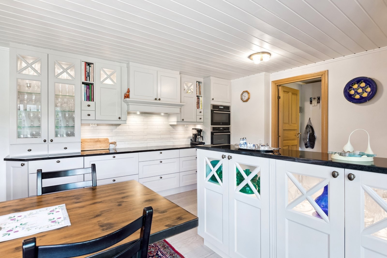 Lys og pen kjøkkeninnredning fra Strai med profilerte fronter og benkeplate i kantslipt Nero Assoluto granitt. Galleribilde