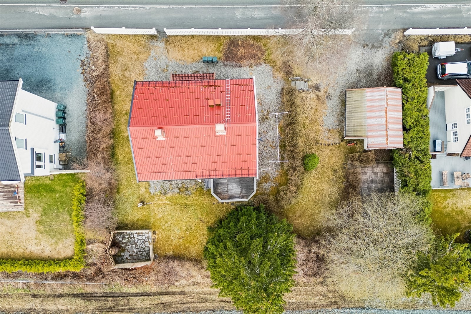 Tomta har gjerde mot veien og hekk mot naboer. Soleplass med skiferdekke til venstre på bildet ligger på kommunens tomt og må påregnes fjernet. Galleribilde