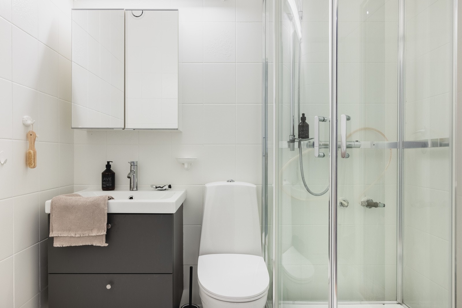 Badet er praktisk og inneholder dusjkabinett, toalett, opplegg for vaskemaskin og servant med speil pg belysning. Galleribilde