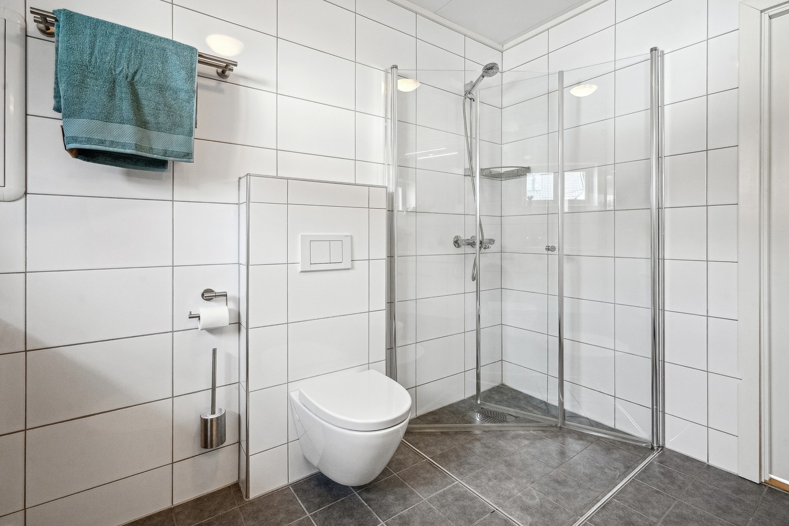 Vegghengt toalett og innfellbare glassdører i dusjssone. Galleribilde