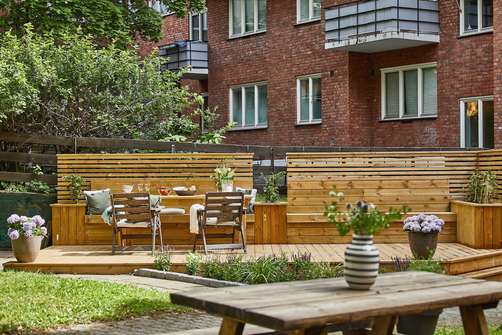 Bakgården er pent opparbeidet med belegningsstein, støttemur, plen, prydbusker, sittegruppe, sykkelparkering, m.m. (arkivbilde) Galleribilde