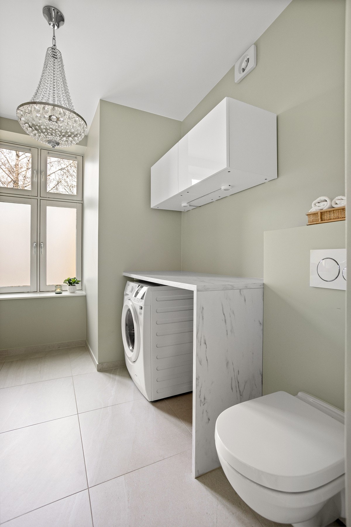 Opplegg for vaskemaskin og tørketrommel under benkeplate og vegghengte skap for oppbevaring. Galleribilde