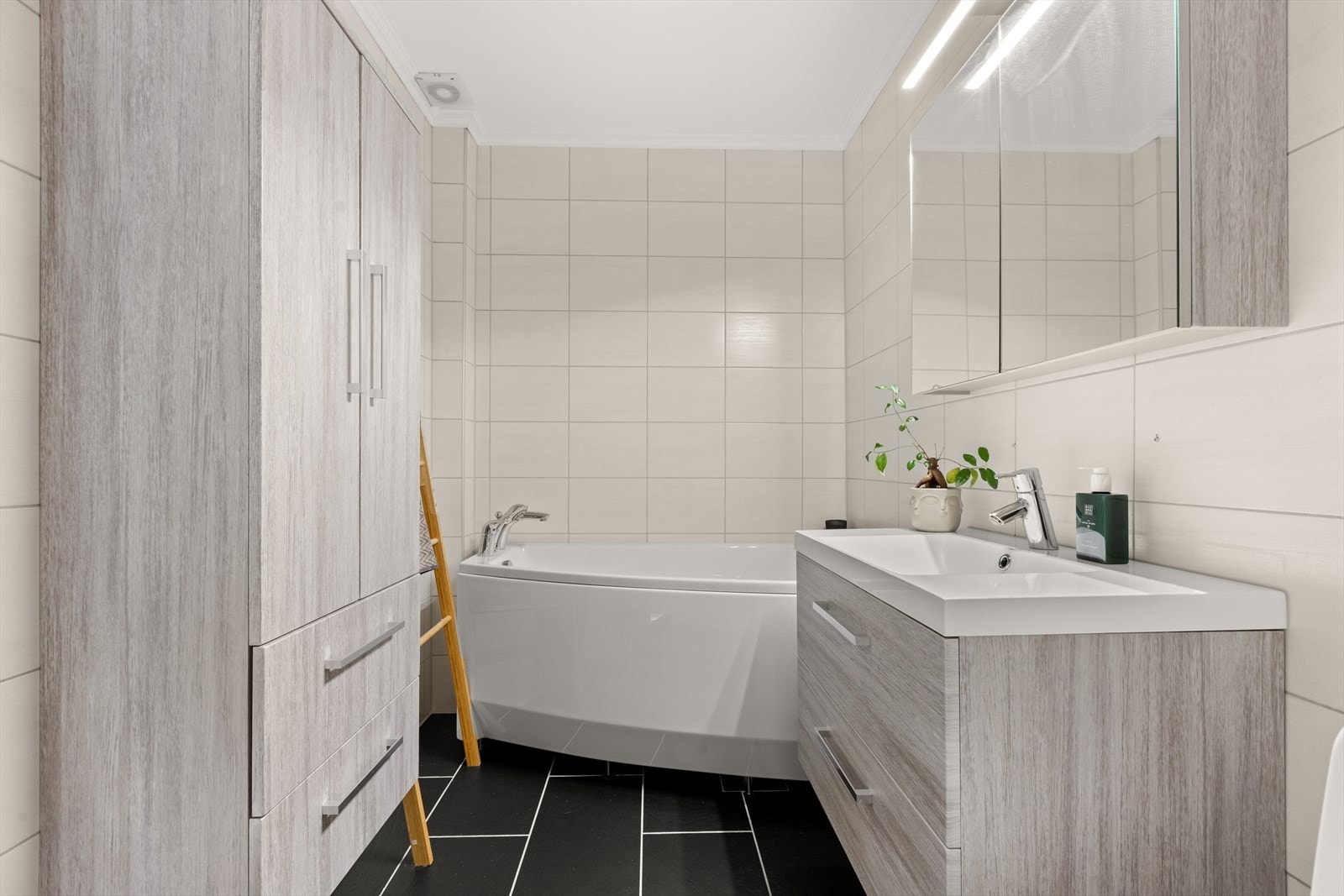 Pent flislagt bad med gulvvarme. Badet er innredet med servantmøbel, høyskap, toalett og badekar. Galleribilde