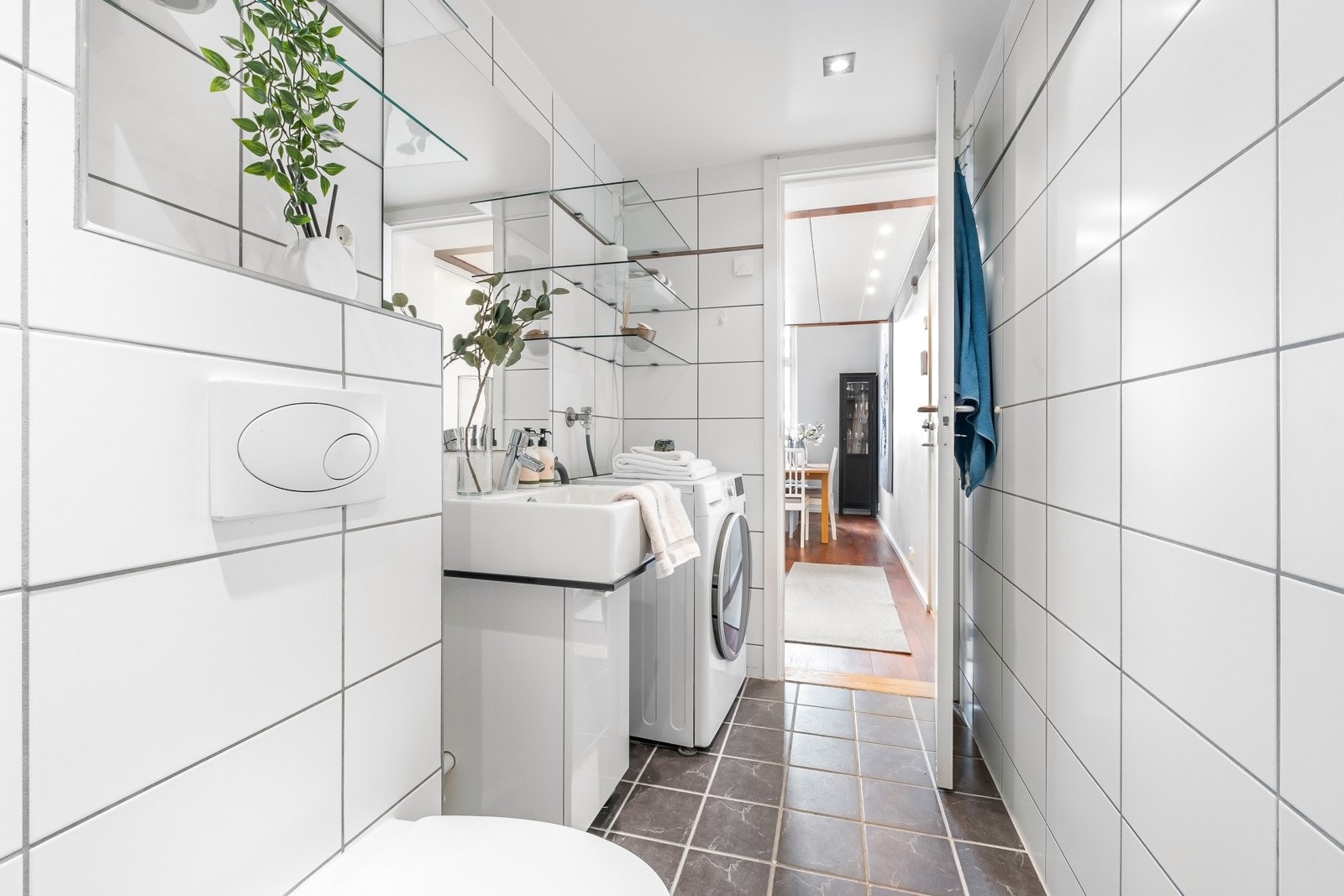 Badet har også veggmontert toalett, dusjnisje med skyvedører som kan foldes inn i glass og opplegg for vaskemaskin. Galleribilde